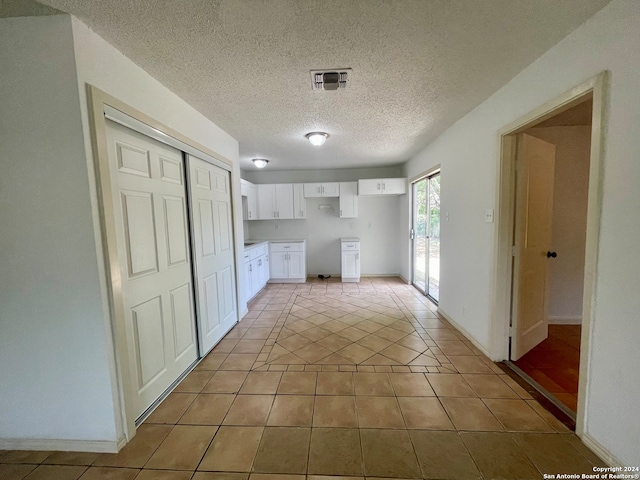 hall with light tile patterned flooring and a textured ceiling