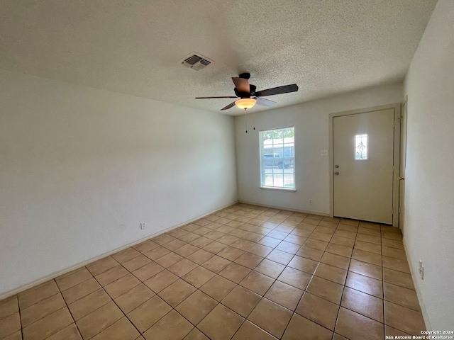 tiled spare room with a textured ceiling and ceiling fan