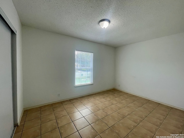 tiled empty room featuring a textured ceiling