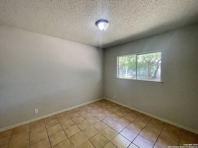 unfurnished room featuring light tile patterned floors, baseboards, and a textured ceiling