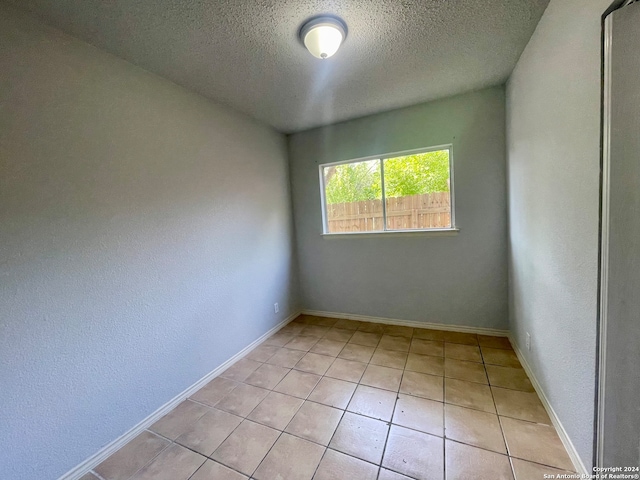 spare room featuring light tile patterned flooring and a textured ceiling