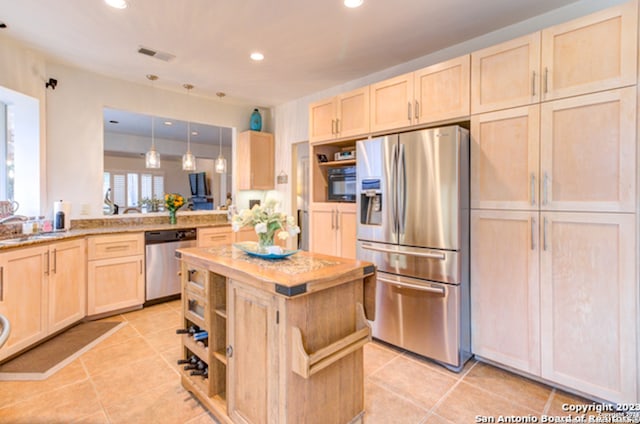 kitchen featuring hanging light fixtures, light tile patterned floors, light brown cabinets, kitchen peninsula, and stainless steel appliances