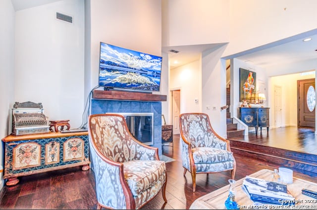 living area featuring high vaulted ceiling, hardwood / wood-style floors, and a tile fireplace