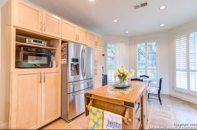 kitchen with light tile patterned floors, stainless steel fridge, oven, and light brown cabinets