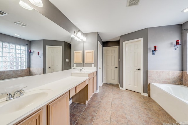 bathroom with tile patterned floors, a tub to relax in, and vanity