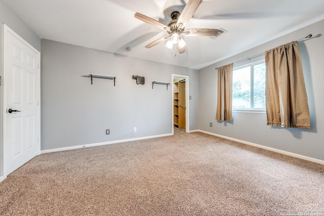 unfurnished bedroom with ceiling fan, a spacious closet, a closet, and carpet