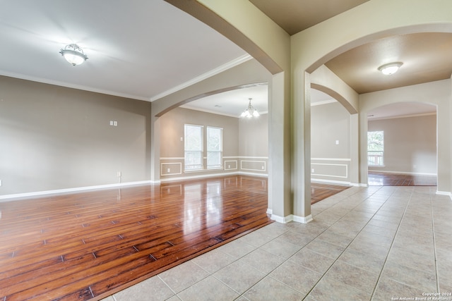 empty room featuring light hardwood / wood-style floors, ornamental molding, and an inviting chandelier