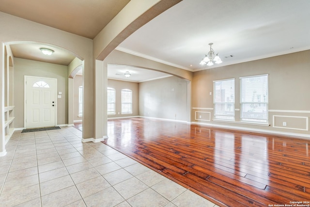 foyer entrance featuring a notable chandelier, ornamental molding, and light wood-type flooring