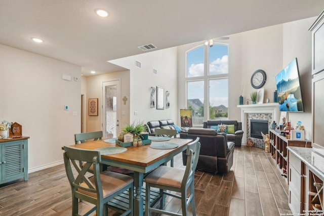 dining area featuring a stone fireplace and a high ceiling