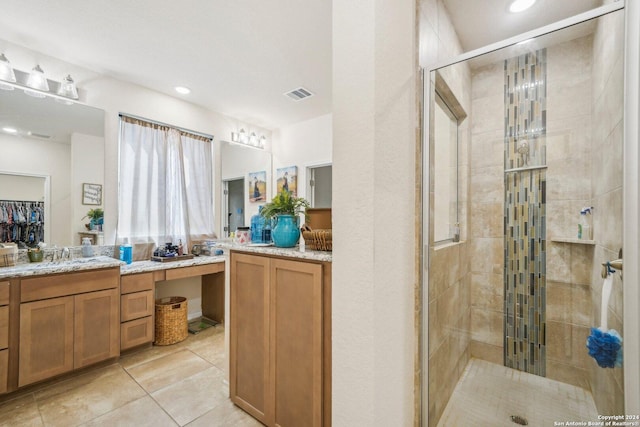 bathroom featuring a shower with door, vanity, and tile patterned floors