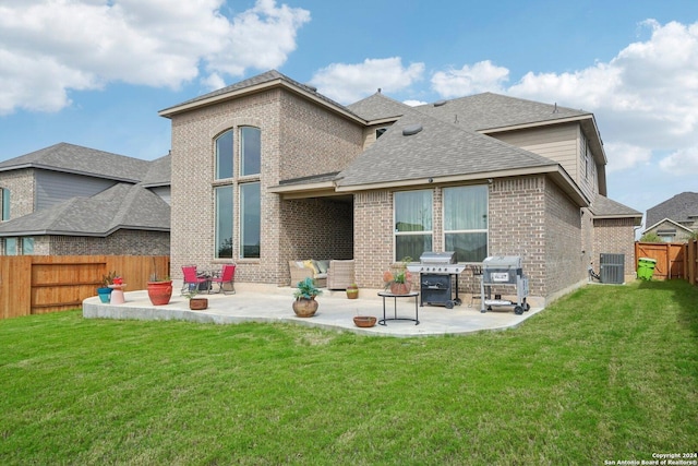 rear view of property featuring a yard, central AC unit, and a patio area