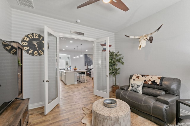 living room with sink, light hardwood / wood-style flooring, ceiling fan, and french doors