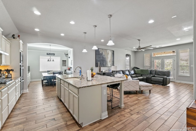 kitchen featuring decorative light fixtures, an island with sink, sink, a kitchen bar, and stainless steel appliances