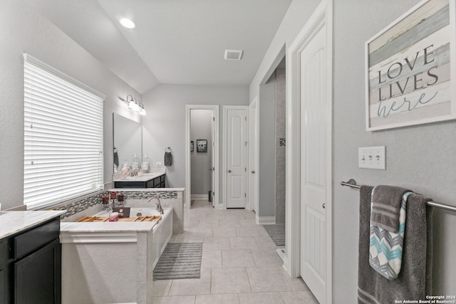 bathroom featuring vanity, tile patterned flooring, lofted ceiling, and a tub