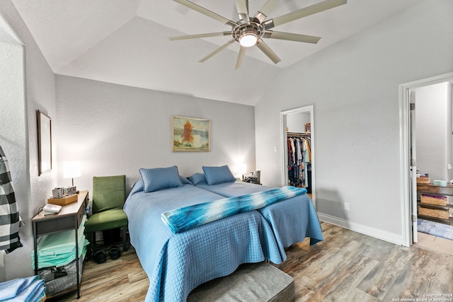 bedroom featuring vaulted ceiling, a walk in closet, light hardwood / wood-style floors, and a closet