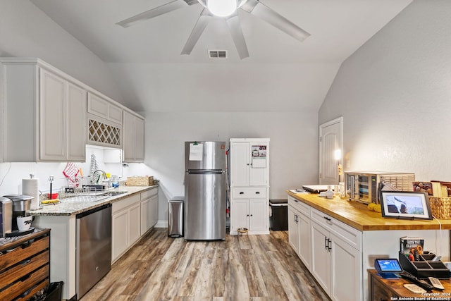 kitchen with white cabinetry, stainless steel appliances, wooden counters, and lofted ceiling