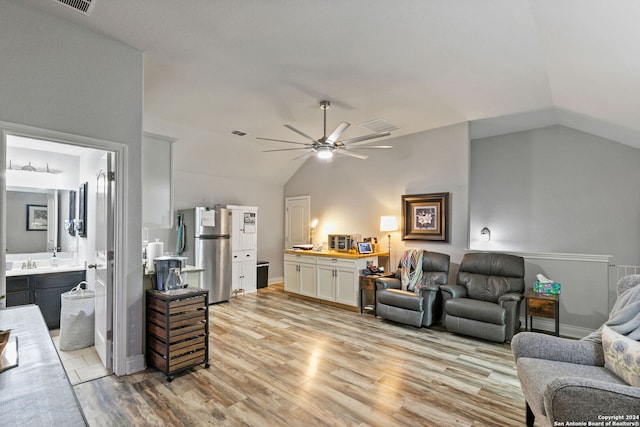 living room featuring ceiling fan, sink, vaulted ceiling, and light hardwood / wood-style flooring