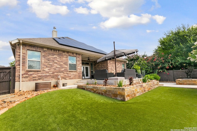 rear view of property with a lawn, a patio, and solar panels