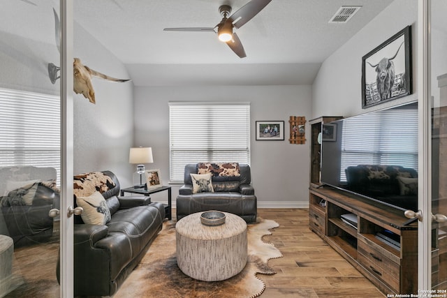 living room with ceiling fan, vaulted ceiling, and light hardwood / wood-style flooring