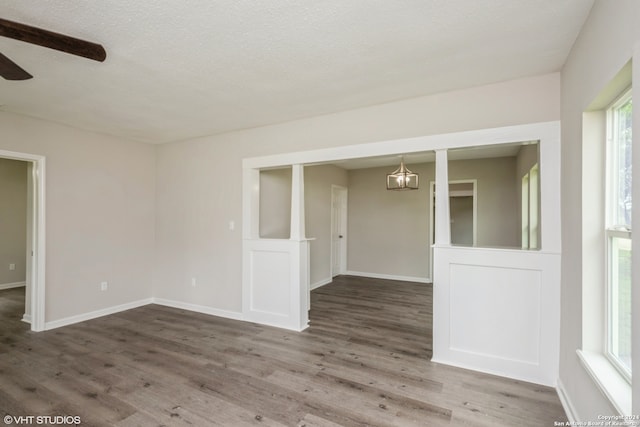 empty room featuring a textured ceiling, ceiling fan with notable chandelier, and hardwood / wood-style floors