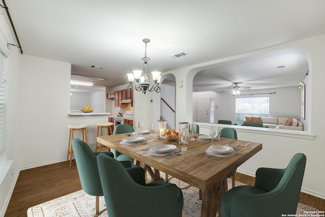 dining space with ceiling fan with notable chandelier and dark hardwood / wood-style flooring