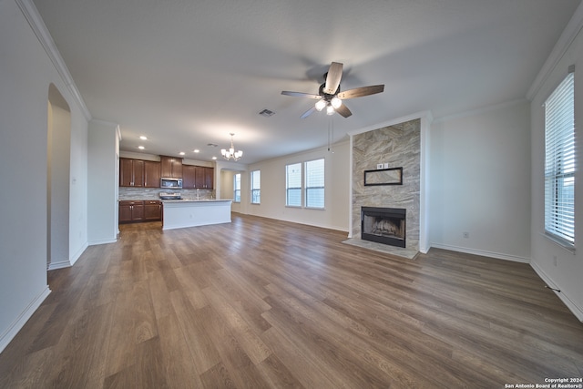 unfurnished living room with plenty of natural light, a fireplace, hardwood / wood-style flooring, and ceiling fan with notable chandelier