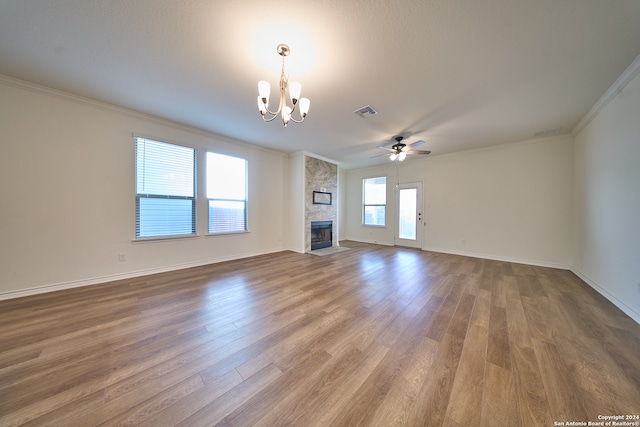 unfurnished living room with ceiling fan with notable chandelier, wood-type flooring, ornamental molding, and a large fireplace