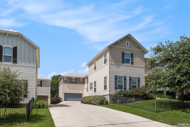 view of front of house featuring a garage, a front lawn, board and batten siding, and fence