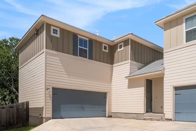 view of front of house with a garage, driveway, fence, and board and batten siding