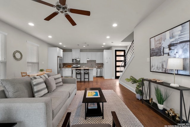 living area with dark wood-type flooring, recessed lighting, stairway, and baseboards