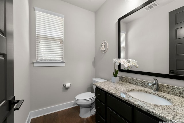 bathroom with visible vents, toilet, vanity, wood finished floors, and baseboards