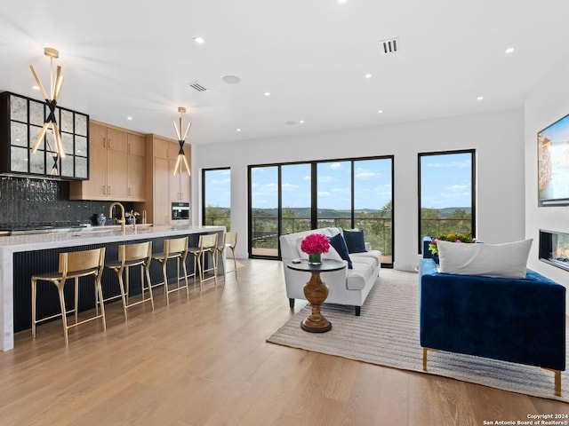 living room featuring recessed lighting, visible vents, a glass covered fireplace, and light wood finished floors