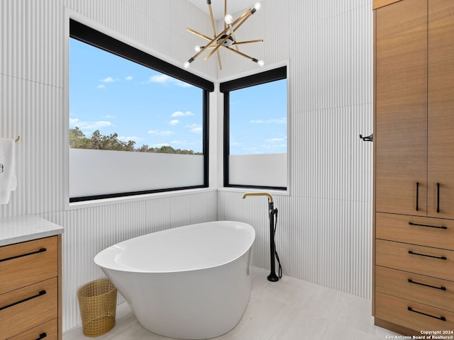 bathroom featuring a notable chandelier, vanity, tile patterned flooring, and a tub