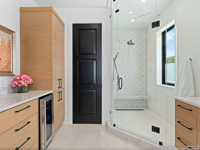 bathroom featuring a shower with shower door, tile patterned floors, vanity, and wine cooler