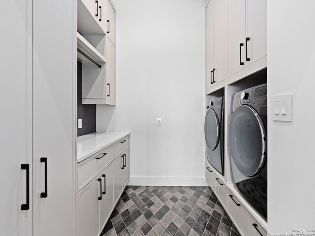 laundry area with washing machine and dryer, dark tile patterned floors, and cabinets