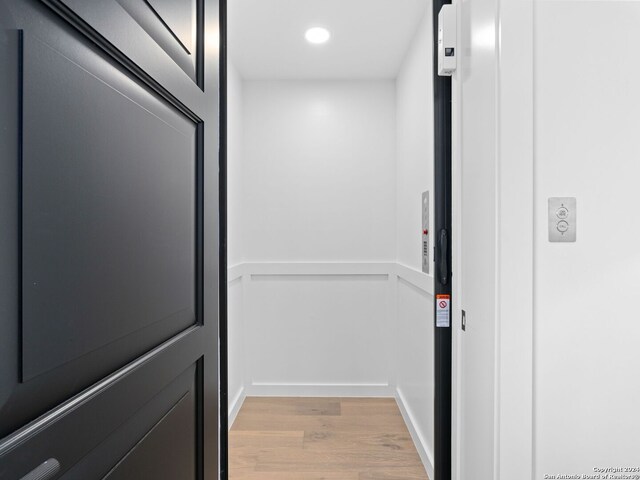 details with elevator and hardwood / wood-style flooring