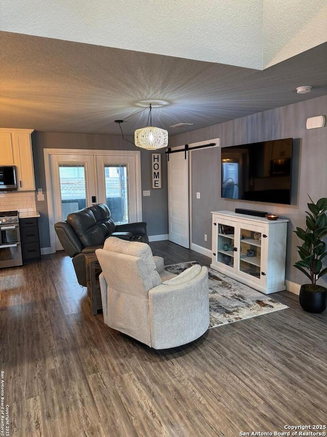 living room featuring dark hardwood / wood-style floors, a barn door, and a textured ceiling