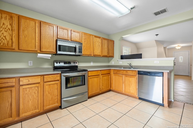 kitchen featuring kitchen peninsula, sink, light tile patterned floors, and stainless steel appliances