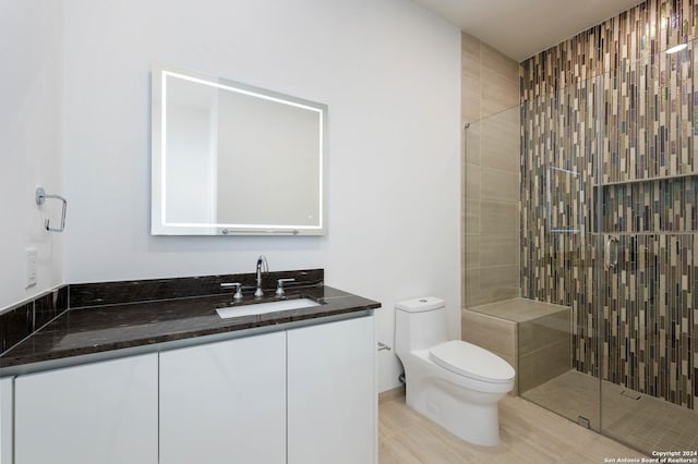 bathroom featuring tiled shower, tile patterned flooring, toilet, and vanity