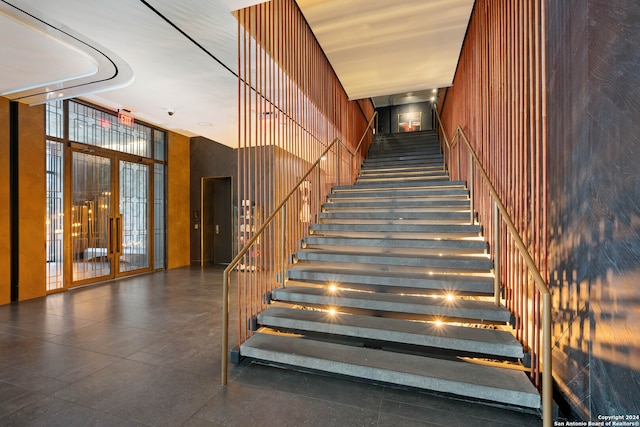 stairway featuring elevator, french doors, and a high ceiling