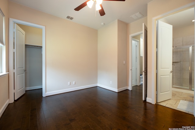 unfurnished bedroom with a spacious closet, a closet, connected bathroom, ceiling fan, and wood-type flooring