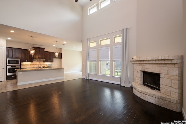 unfurnished living room featuring a stone fireplace, tile patterned floors, and a towering ceiling