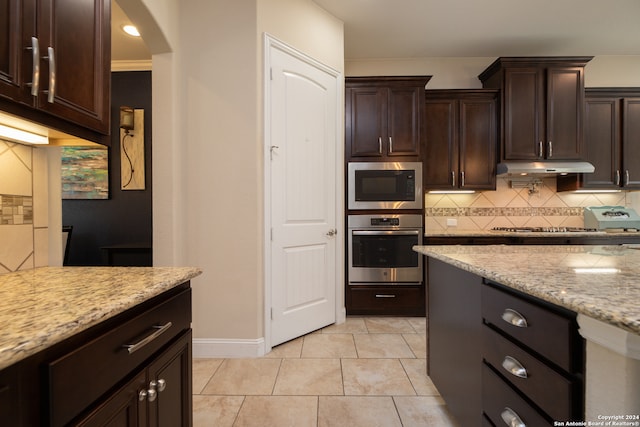 kitchen with tasteful backsplash, dark brown cabinets, light tile patterned floors, oven, and light stone countertops