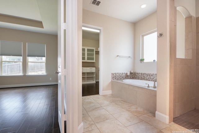 bathroom featuring a relaxing tiled tub and hardwood / wood-style flooring