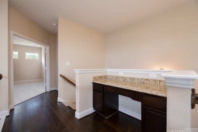 interior space featuring kitchen peninsula, light stone countertops, and dark hardwood / wood-style floors