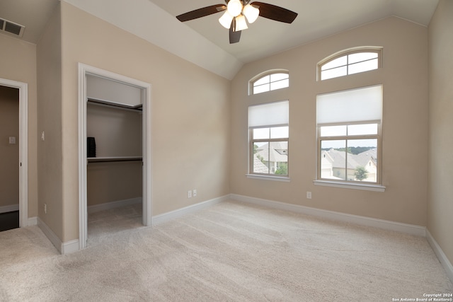 unfurnished bedroom featuring lofted ceiling, ceiling fan, a spacious closet, light colored carpet, and a closet