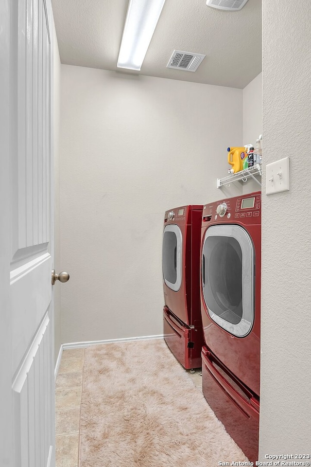 laundry area featuring washing machine and dryer, a textured ceiling, and carpet flooring