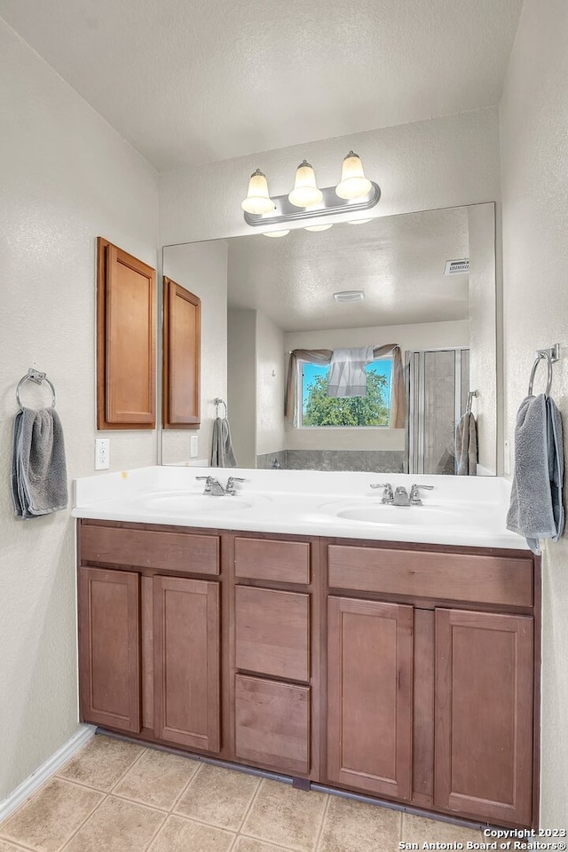 bathroom with tile patterned floors, a textured ceiling, and dual bowl vanity