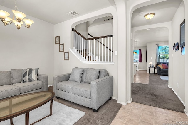 carpeted living room featuring an inviting chandelier