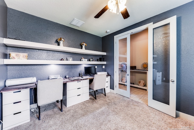 carpeted home office featuring french doors, ceiling fan, and built in desk